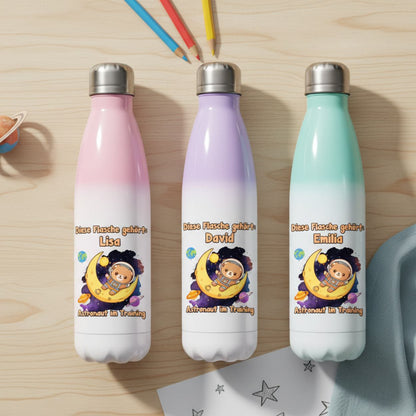 Drei personalisierte Kinder-Trinkflaschen in Rosa, Lila und Mint liegen ordentlich nebeneinander auf hellem Holztisch, Vogelperspektive.
